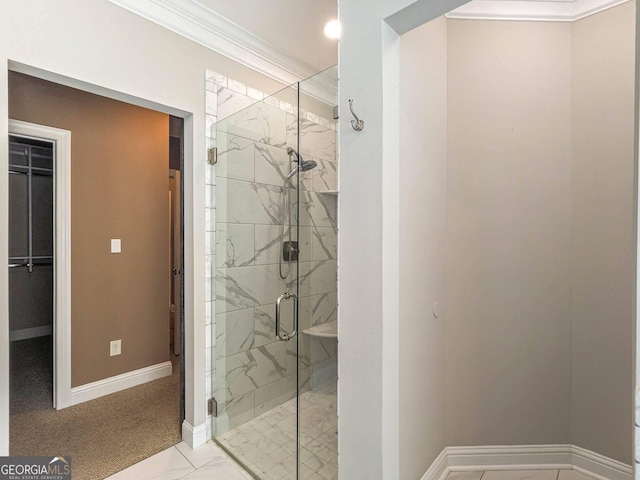 bathroom featuring a marble finish shower, baseboards, ornamental molding, and a walk in closet