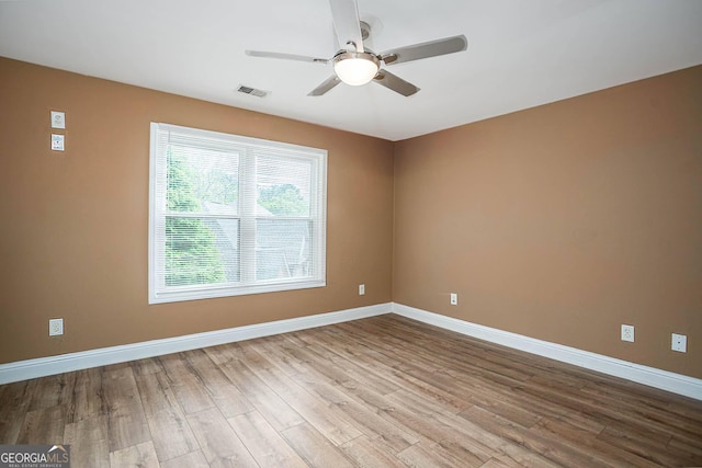 unfurnished room with visible vents, baseboards, a ceiling fan, and wood finished floors