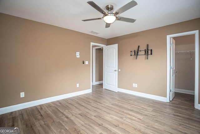 unfurnished bedroom with visible vents, baseboards, a closet, a spacious closet, and wood finished floors