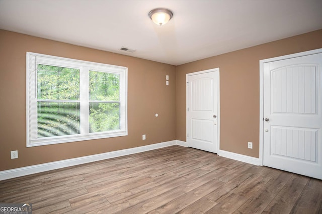 unfurnished bedroom with light wood finished floors, visible vents, and baseboards
