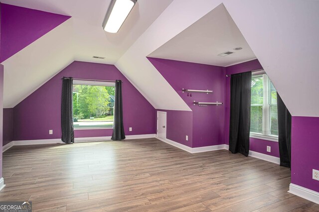 additional living space with a wealth of natural light, visible vents, wood finished floors, and lofted ceiling