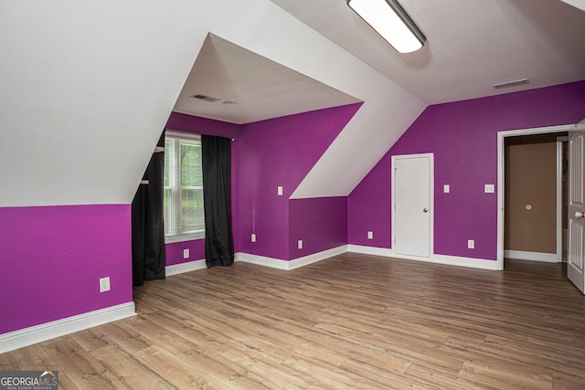 bonus room featuring visible vents, vaulted ceiling, and wood finished floors