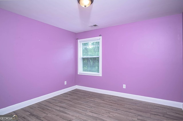 spare room featuring visible vents, baseboards, and wood finished floors