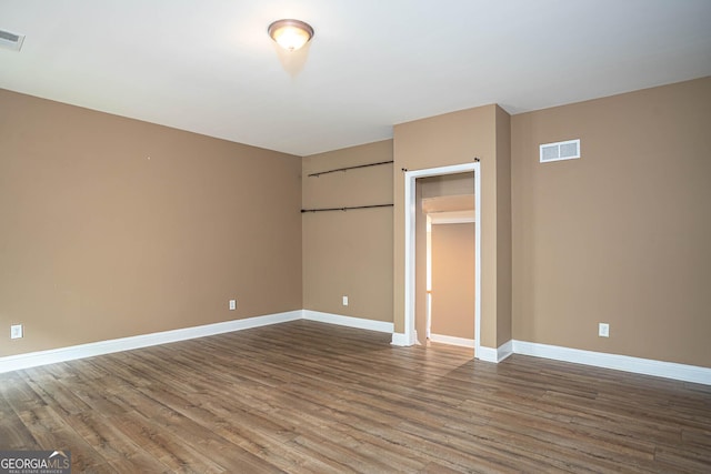 unfurnished bedroom with wood finished floors, baseboards, and visible vents