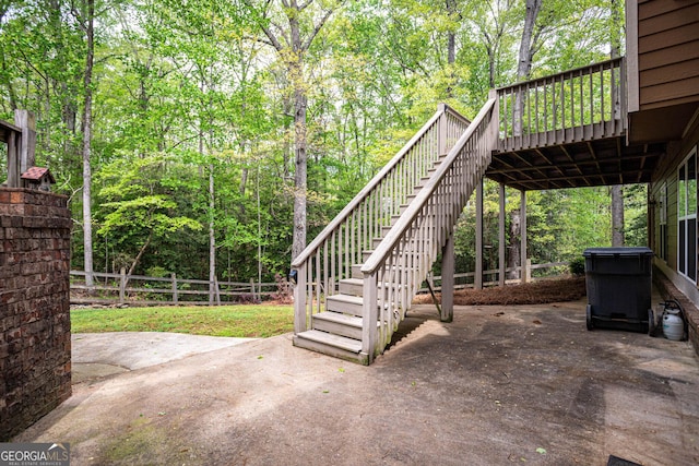view of patio / terrace with a forest view, fence, a deck, and stairs