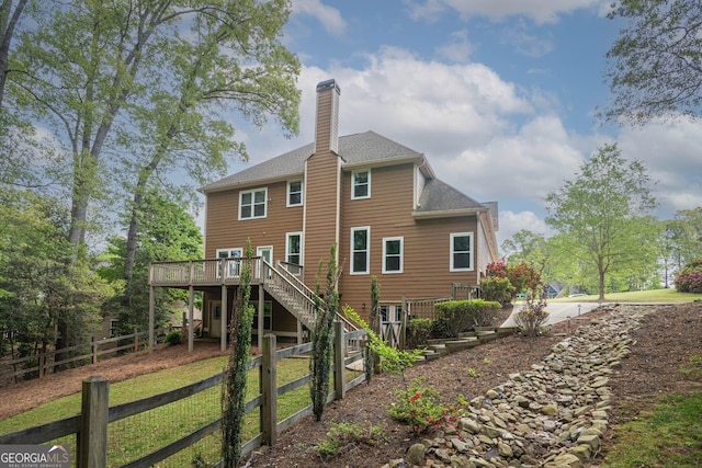 back of house featuring fence private yard, stairway, a chimney, a shingled roof, and a deck