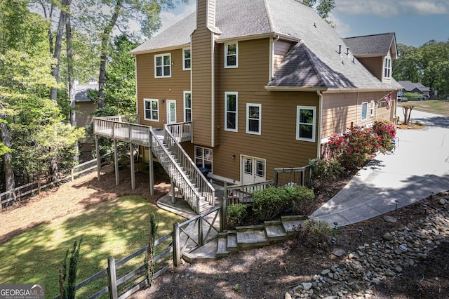 back of property with a chimney, stairs, a wooden deck, fence, and a shingled roof
