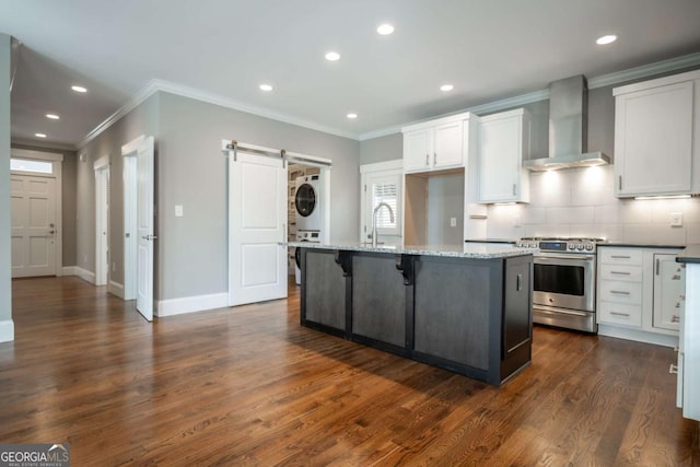 215 Chapman Pl, Athens, GA 30606 - kitchen with stainless steel gas range oven, stacked washer / drying machine, wall chimney range hood, a barn door, and white cabinetry