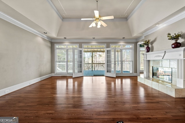 unfurnished living room with crown molding, wood finished floors, a raised ceiling, and a ceiling fan