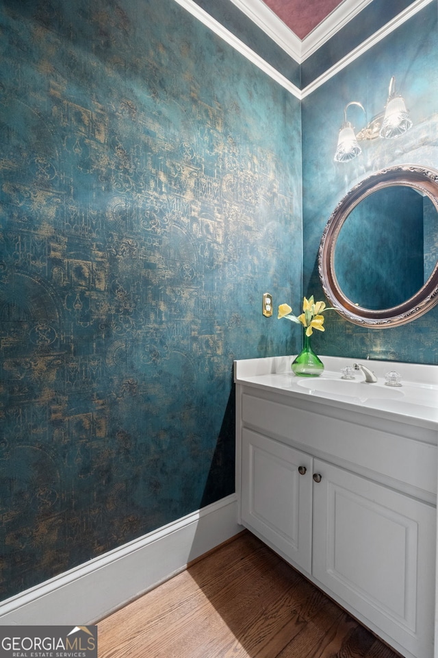 bathroom with baseboards, crown molding, wood finished floors, and vanity
