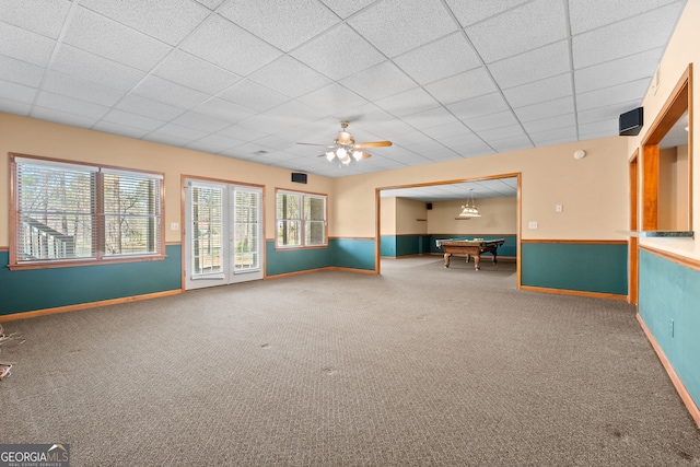unfurnished living room with pool table, baseboards, ceiling fan, carpet, and a drop ceiling