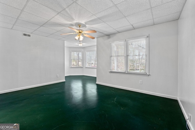 empty room with baseboards, ceiling fan, visible vents, and a paneled ceiling