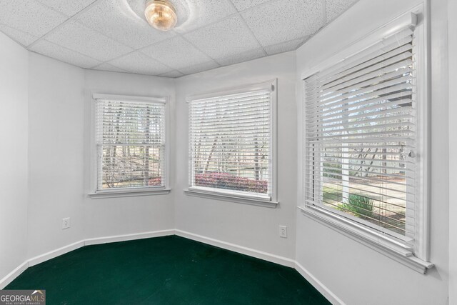 unfurnished room with baseboards and a drop ceiling