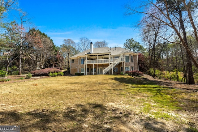 rear view of property with a chimney, a deck, stairs, and a lawn