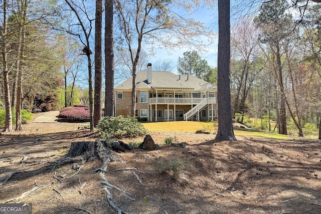 back of house featuring a chimney, a yard, stairs, and a deck