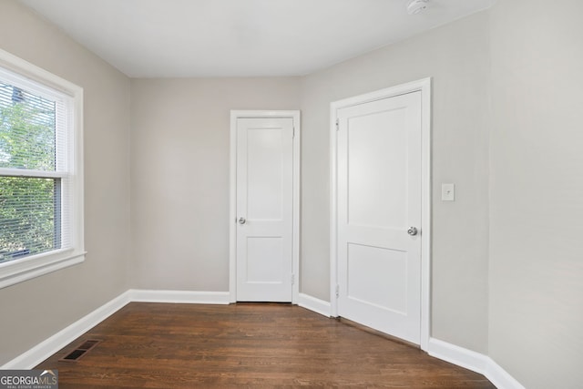 1013 Columbia Dr, Decatur, GA 30030 - unfurnished bedroom featuring multiple windows and dark wood-style floors