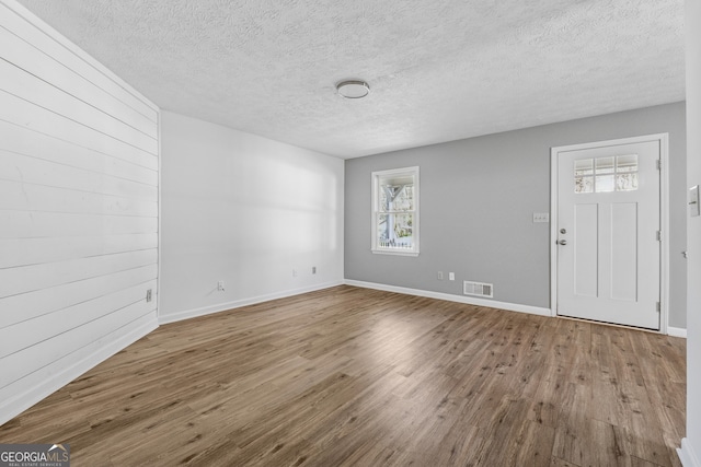 entryway featuring wood finished floors, a textured ceiling, baseboards, and visible vents