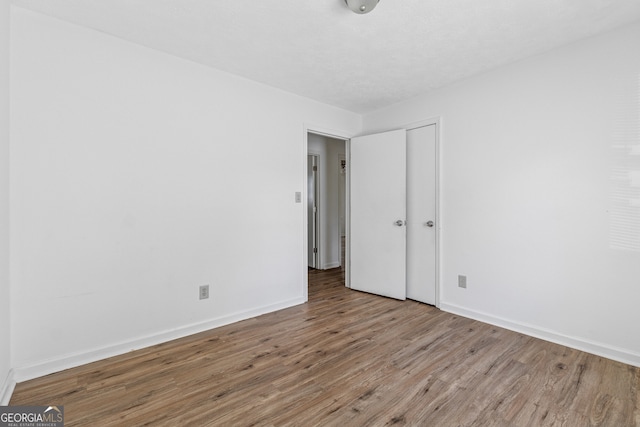 unfurnished bedroom featuring baseboards, a closet, and wood finished floors