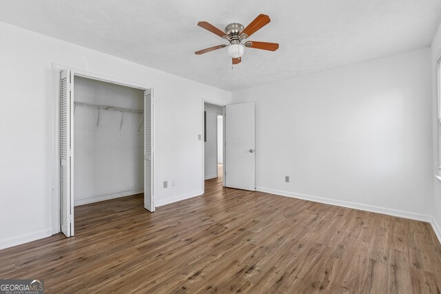 unfurnished bedroom with baseboards, a closet, ceiling fan, and wood finished floors