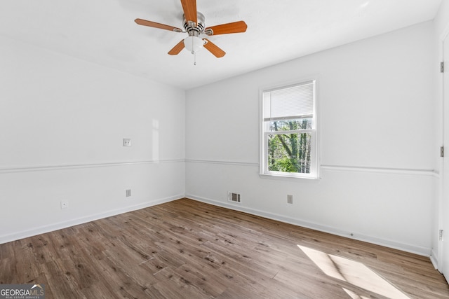 unfurnished room with a ceiling fan, visible vents, baseboards, and wood finished floors