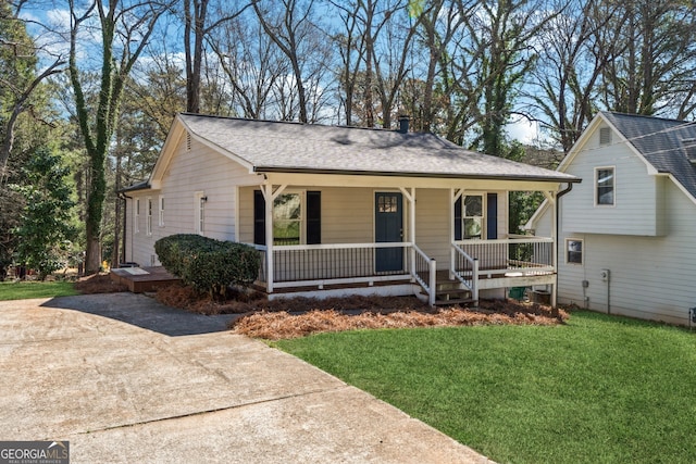 view of front of house featuring a chimney, a shingled roof, a porch, and a front yard