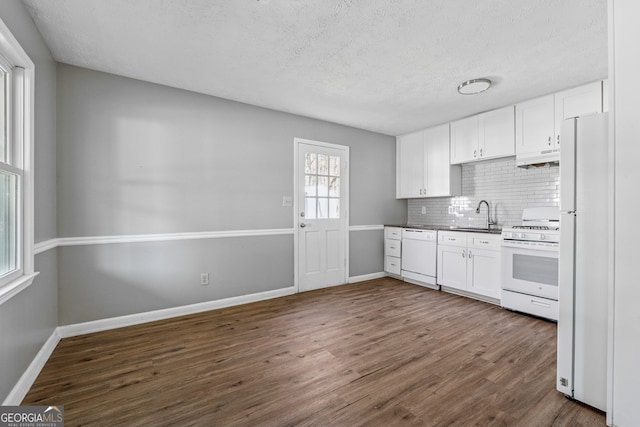 kitchen featuring a sink, tasteful backsplash, dark wood-style floors, white appliances, and white cabinets