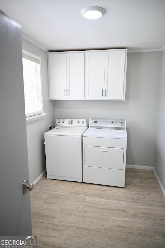 washroom with baseboards, separate washer and dryer, cabinet space, and light wood-type flooring