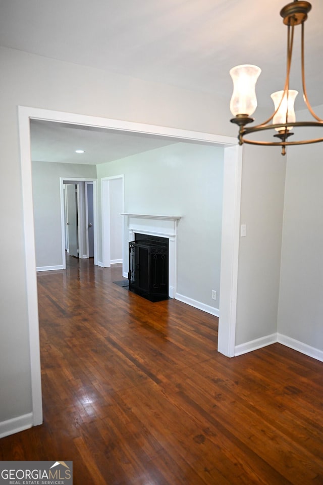 unfurnished living room with hardwood / wood-style floors, baseboards, a fireplace with flush hearth, and a chandelier