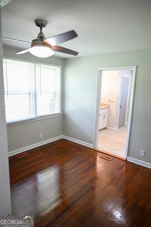 unfurnished room with a ceiling fan, wood finished floors, baseboards, and visible vents
