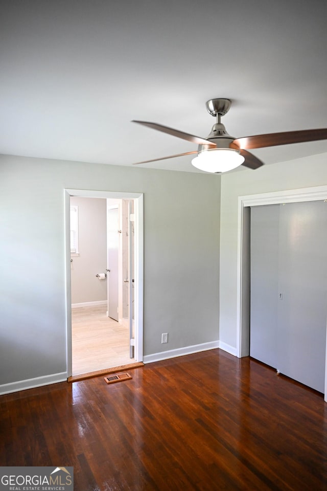 unfurnished bedroom featuring baseboards, visible vents, wood finished floors, and a closet
