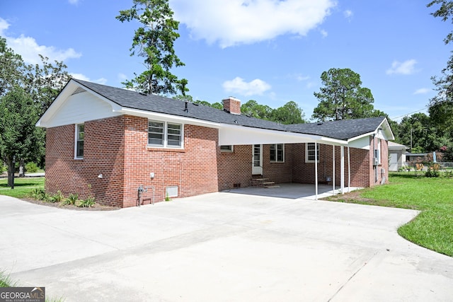rear view of property featuring driveway, brick siding, crawl space, and a carport