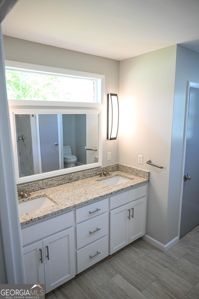 bathroom with double vanity, a sink, toilet, and a shower