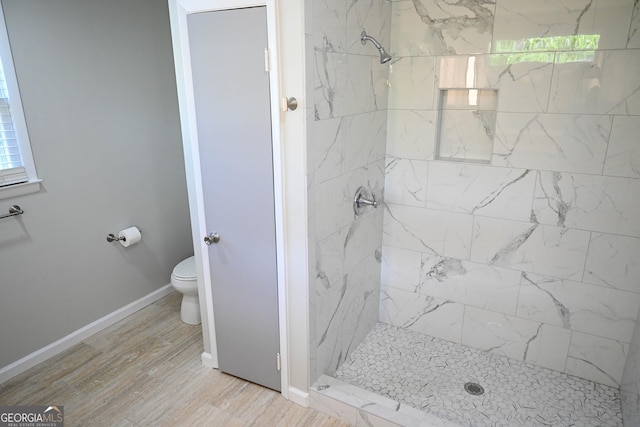 bathroom featuring toilet, wood finished floors, baseboards, and a shower stall