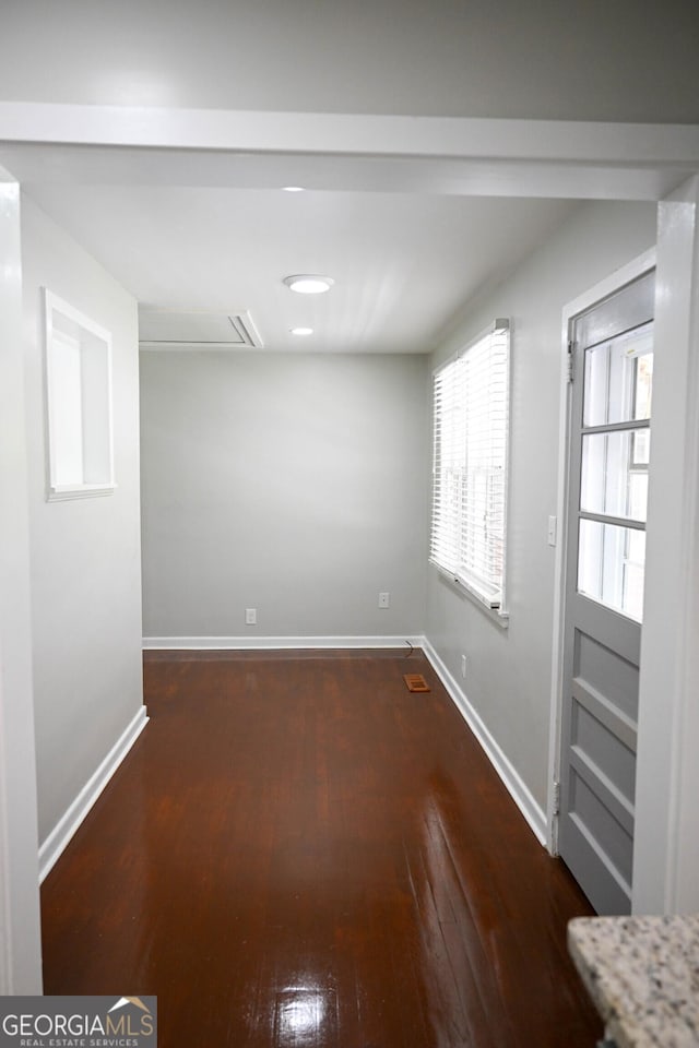 spare room with baseboards and dark wood finished floors