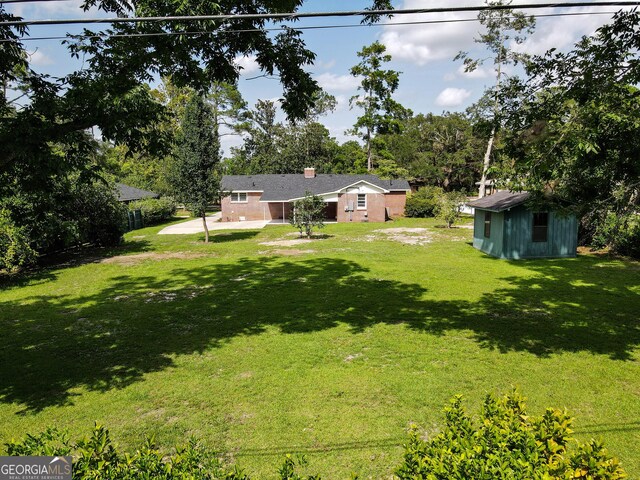 view of yard featuring an outbuilding, a storage unit, and a patio area