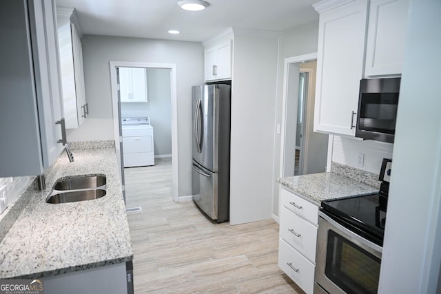 kitchen featuring light stone counters, light wood finished floors, washer / clothes dryer, stainless steel appliances, and white cabinets