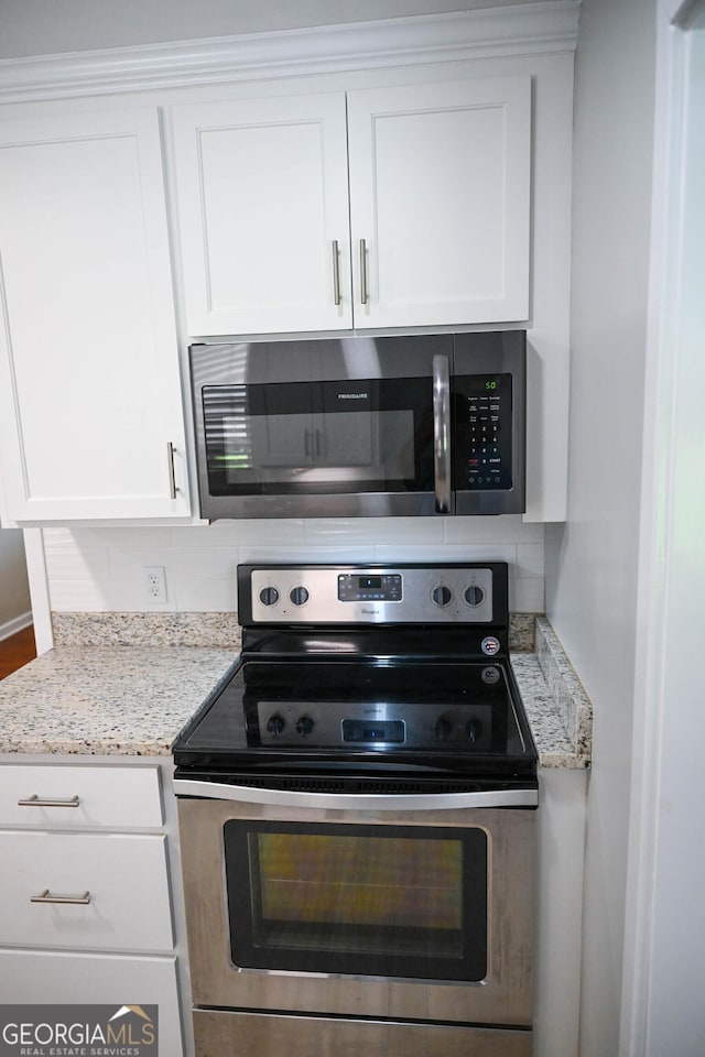 kitchen featuring backsplash, white cabinets, appliances with stainless steel finishes, and light stone counters