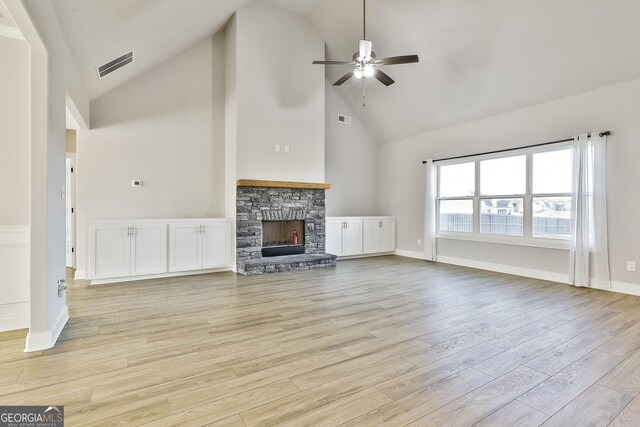 8 Sumner Way, Senoia, GA 30276 - unfurnished living room with visible vents, light wood-style floors, a stone fireplace, ceiling fan, and high vaulted ceiling