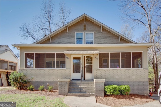 bungalow-style home featuring brick siding, a sunroom, and entry steps