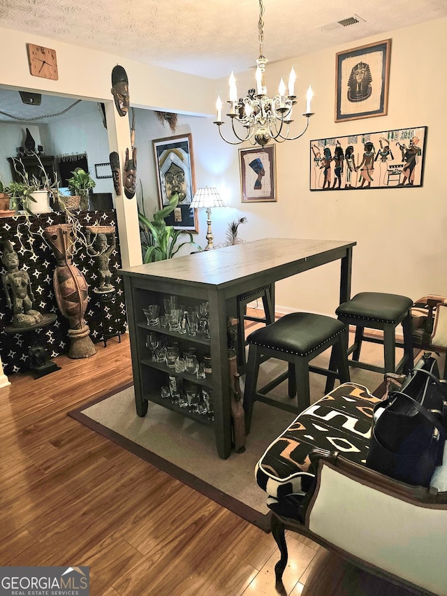315 Saratoga Pl, Riverdale, GA 30296 - dining area featuring a textured ceiling, wood finished floors, visible vents, and a notable chandelier