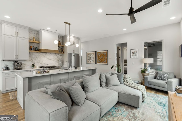 living room with light wood-type flooring, recessed lighting, ceiling fan, and visible vents
