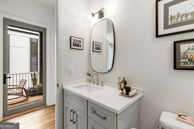 half bathroom featuring wood finished floors, toilet, and vanity