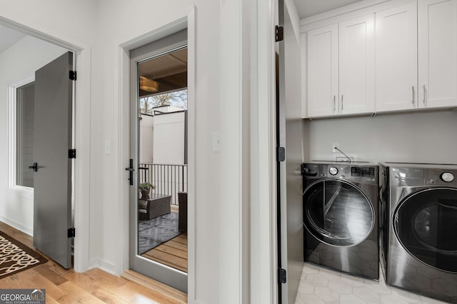 washroom featuring washer and clothes dryer, light wood-style floors, and cabinet space