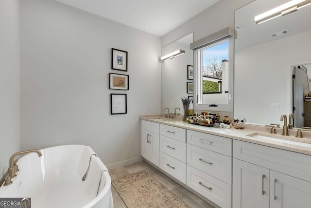 full bathroom with a freestanding tub, baseboards, a sink, visible vents, and double vanity