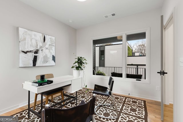 office space featuring baseboards, visible vents, and wood finished floors