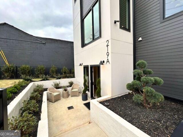 entrance to property with fence, stucco siding, and a patio area
