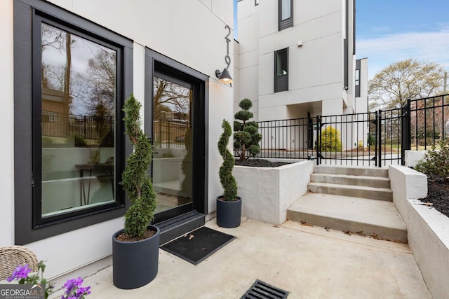 entrance to property featuring stucco siding and fence