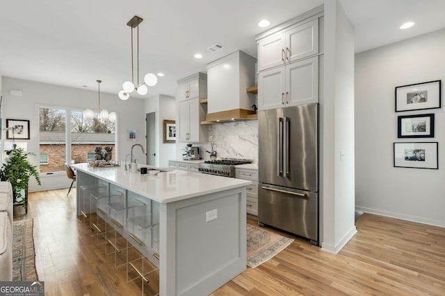kitchen featuring high quality fridge, light countertops, a sink, premium range hood, and range