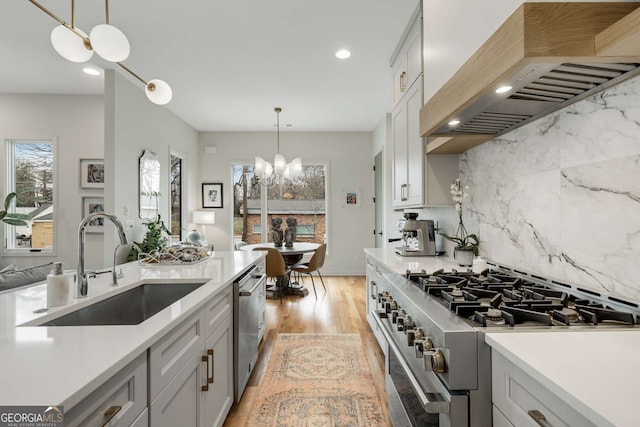 kitchen with light countertops, a sink, custom range hood, and appliances with stainless steel finishes