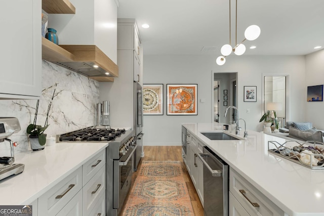 kitchen featuring a sink, open shelves, light wood finished floors, wall chimney exhaust hood, and stainless steel appliances
